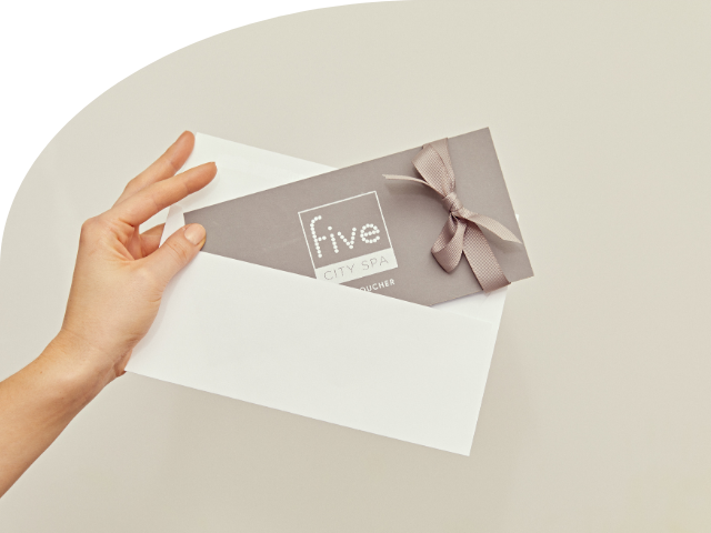 A hand holding a Five City Spa voucher